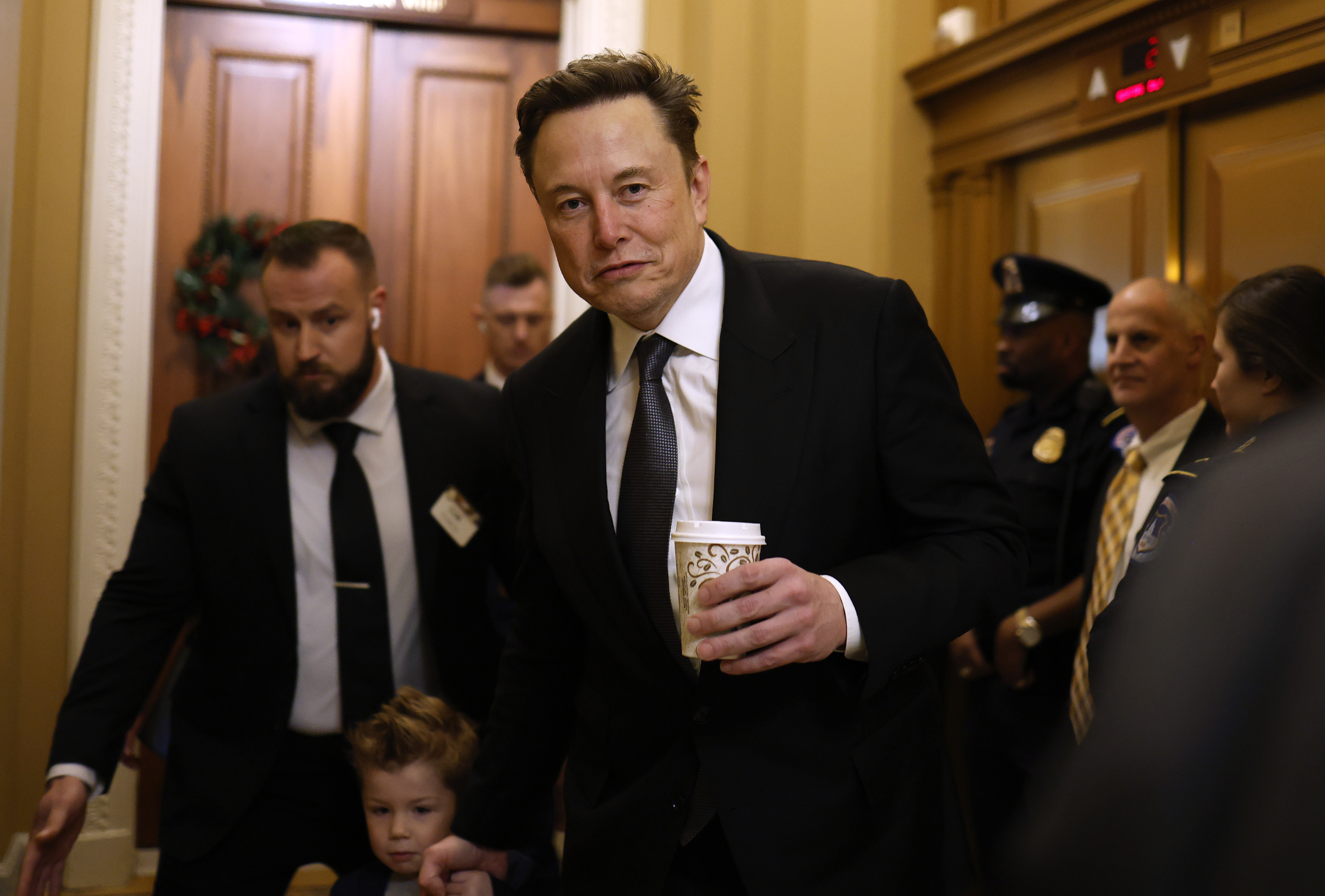 WASHINGTON, DC - DECEMBER 05: Tesla CEO Elon Musk, Co-Chair of the newly announced Department of Government Efficiency (DOGE), arrives on Capitol Hill with his son on December 05, 2024 in Washington, DC. Musk and his Co-Chair, businessman Vivek Ramaswamy are meeting with lawmakers today about DOGE, a planned presidential advisory commission with the goal of cutting government spending and increasing efficiency in the federal workforce. (Photo by Anna Moneymaker/Getty Images)