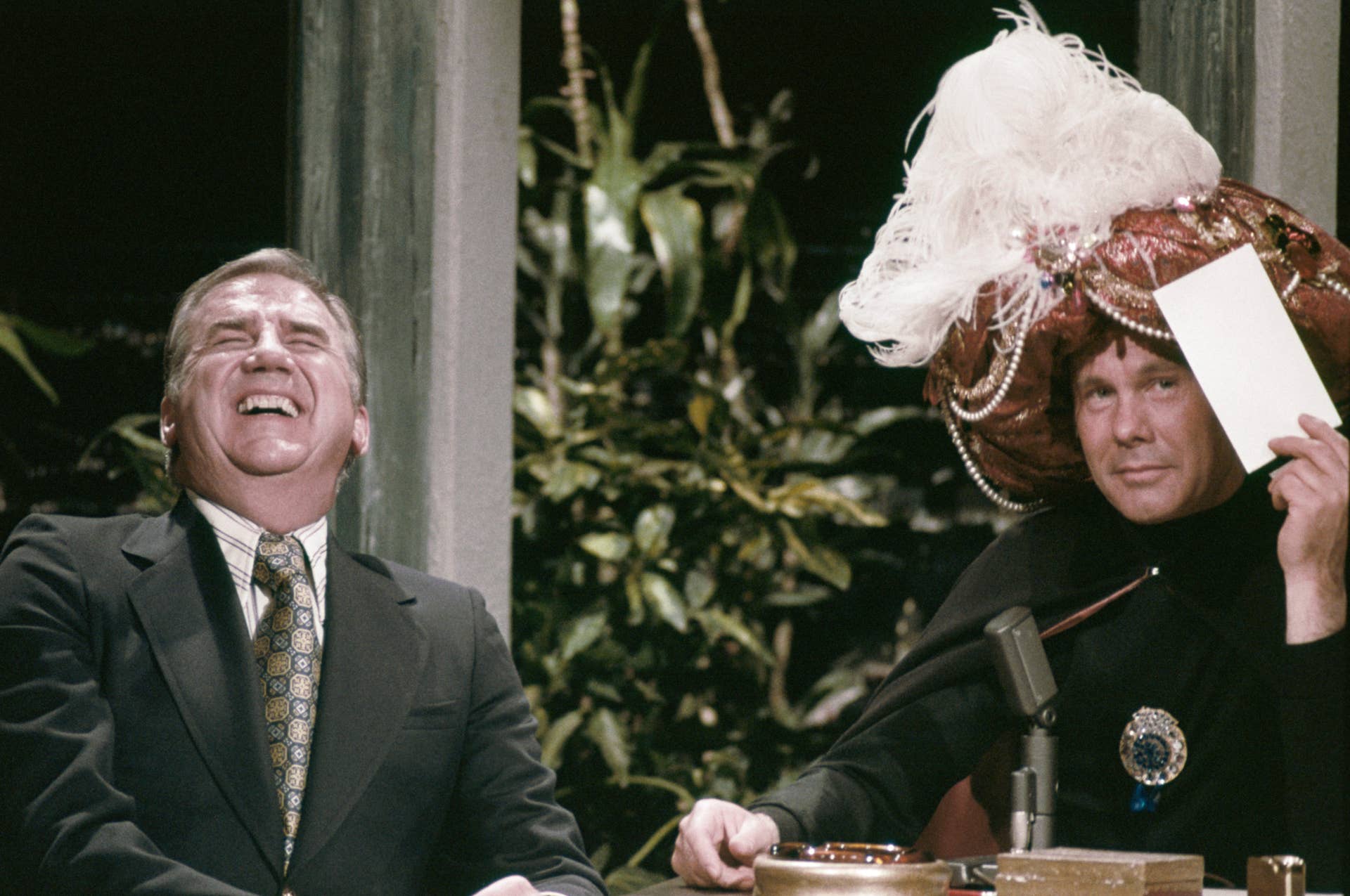 THE TONIGHT SHOW STARRING JOHNNY CARSON -- Pictured: (l-r) Co-host Ed McMahon with host Johnny Carson as Carnac the Magnificent (Photo by NBCU Photo Bank/NBCUniversal via Getty Images via Getty Images)